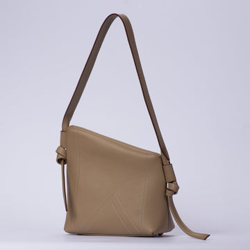 Muted Light Dove Beige Asymmetrical Sculptural Shoulder Bag With Double Chevron Front Stitching, Decorative Knotted Side Carry Straps And Slanted Soft Silhouette