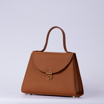 Warm Sienna Tan Textured Trapezoid Top Handle Handbag With Curved Flap Golden Ring Clasp, Base Protective Metal Studs And Side Mount Hardware Loops